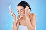 Black woman, water splash for face cleaning, skincare wellness or luxury spa facial beauty in blue background studio. Skin, smile or happy girl model with water splash shower or cosmetics advertising