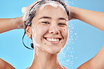 Hair shampoo, portrait and woman in shower in studio isolated on a blue background. Hygiene, water splash and healthy female model from Canada cleaning, bathing and washing for wellness and hair care