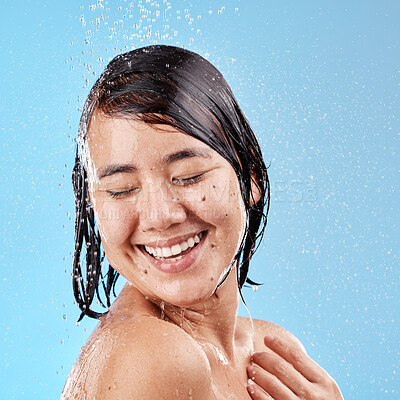 Buy stock photo Shower, water and woman in a studio for skincare, cleaning or wellness with a self care mindset. Cosmetics, beauty and wet Asian model with a skin or body care routine isolated by a blue background.