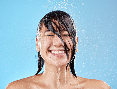 Buy stock photo Shower, woman and water with a face cleaning for clean, wash and hygiene on a blue studio background. Bathroom, showering and asian female cleansing her body for health and wellness in studio