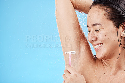 Buy stock photo Shower, underarm and shaving with a model asian woman shaving her armpit in studio on a blue background for grooming. Water, luxury and hair removal with an attractive young female in the bathroom