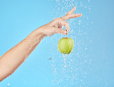 Buy stock photo Apple, water and hand with fruit hanging for vitamin healthcare or nutrition sustainability in studio. Healthy body wellness, detox health and healthy food under water in blue studio background