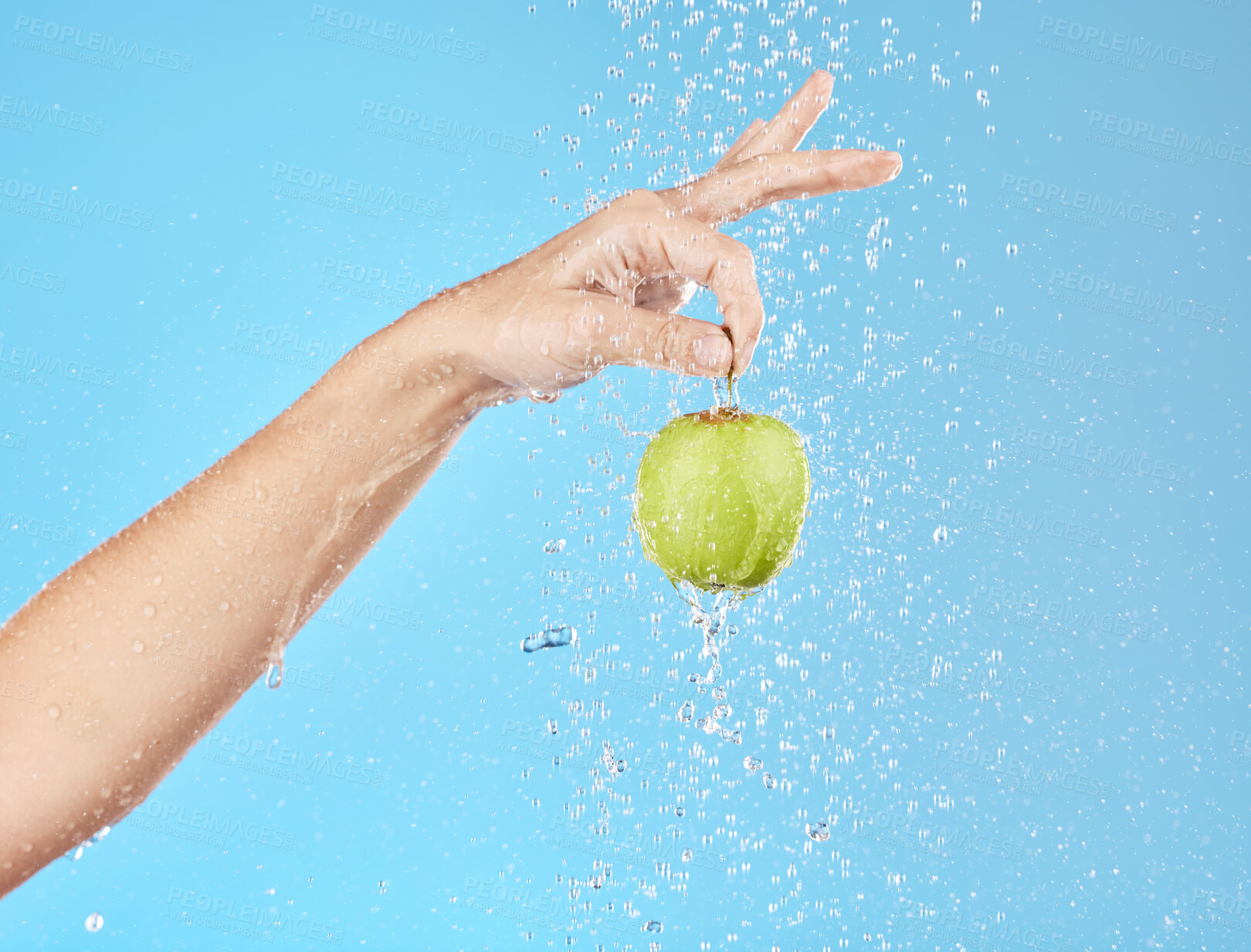 Buy stock photo Apple, water and hand with fruit hanging for vitamin healthcare or nutrition sustainability in studio. Healthy body wellness, detox health and healthy food under water in blue studio background