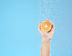 Hand, orange and water with natural skincare for health, wellness and organic fruit on a blue studio background. Beauty, fresh and food for juicy vitamin c skin care treatment for dermatology