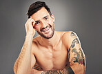 Man, beauty and sexy with body, tattoo and happy portrait against grey studio background with mockup space. Male model, sexy and smile for self care, skincare and cosmetic wellness with clean face