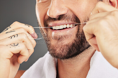 Buy stock photo Floss, dental hygiene and man cleaning teeth, for wellness and against grey studio background. Oral health, healthy male and thin filaments string for fresh breath, remove plaque and mouth healthcare