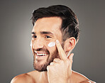 Beauty, sunscreen and face of man with cream product for health, moisturizing and skin hydration. Happy, healthy and skincare lifestyle routine of model on dark gray studio background.