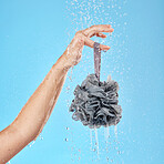 Hand, shower and water with a body sponge for skincare, cleaning and hygiene against a blue studio background. Woman, model and hands holding a skin wash product for advertising with water splash