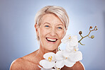 Face, beauty and flowers with a mature woman in studio on a gray background with an orchid for natural care. Portrait, cosmetics and plant with a senior female posing to promote the benefit of nature