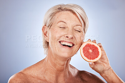 Buy stock photo Skincare, beauty and senior woman with a grapefruit for health, wellness and facial beauty against a grey mockup studio background. Excited, happy and elderly model with a smile for a fruit diet