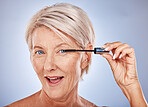 Makeup, mascara and portrait of a senior woman with a natural, cosmetic and beauty routine in a studio. Cosmetics, beautiful and elderly model with a eyelash product isolated by a gray background.