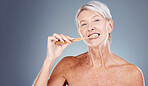 Brushing teeth, portrait and senior woman in studio for dental, mouth and tooth wellness with product marketing, advertising and promotion space. Elderly model with toothbrush for morning care mockup