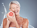 Skincare, water and portrait of old woman with grapefruit in gray background studio for wellness. Beauty, water splash and senior female with fruit for organic, natural and healthy cosmetic products