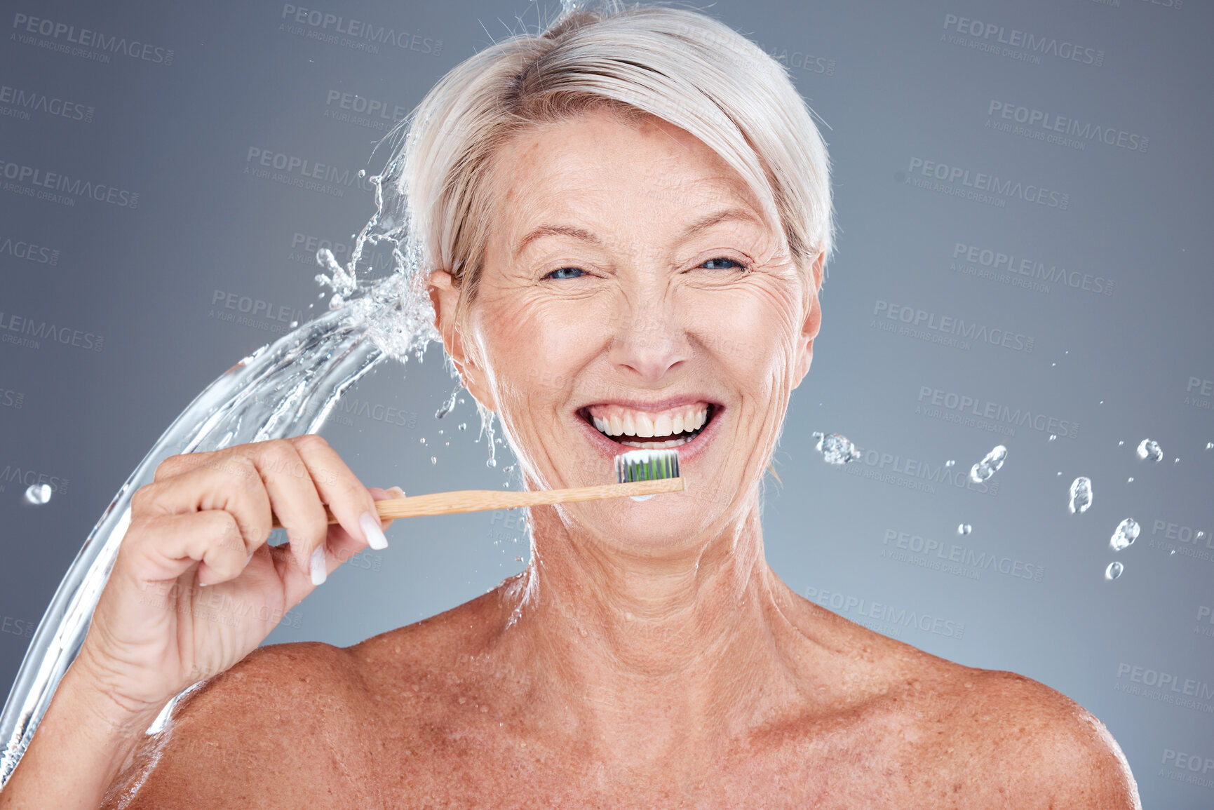 Buy stock photo Wellness, water splash and portrait of old woman brushing teeth isolated on gray background in studio. Bamboo, dental care and senior female cleaning teeth with toothbrush for eco friendly hygiene