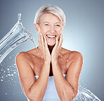 Mature woman, wet or water splash in skincare grooming, morning cleaning routine or healthcare wellness on gray studio background. Portrait, smile or happy elderly beauty model with water drop motion