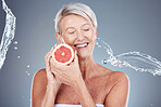 Wellness, beauty and grapefruit woman with water splash for body care, skincare and health cosmetics marketing. Clean, happy and healthy senior model for cosmetic advertising on gray studio mockup.