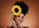 Flower, beauty and woman or portrait for skincare, haircare and natural health or wellness. Sunflower, nature and black woman on a brown studio background for organic skin care or bodycare 