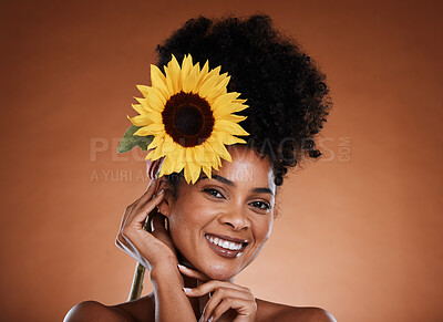 Buy stock photo Flower, beauty and woman or portrait for skincare, haircare and natural health or wellness. Sunflower, nature and black woman on a brown studio background for organic skin care or bodycare 