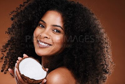 Buy stock photo Beauty, coconut and woman skincare or hair care with happy smile or curls for natural oil and brown studio background. Portrait, African American model and happiness with fruit and afro product