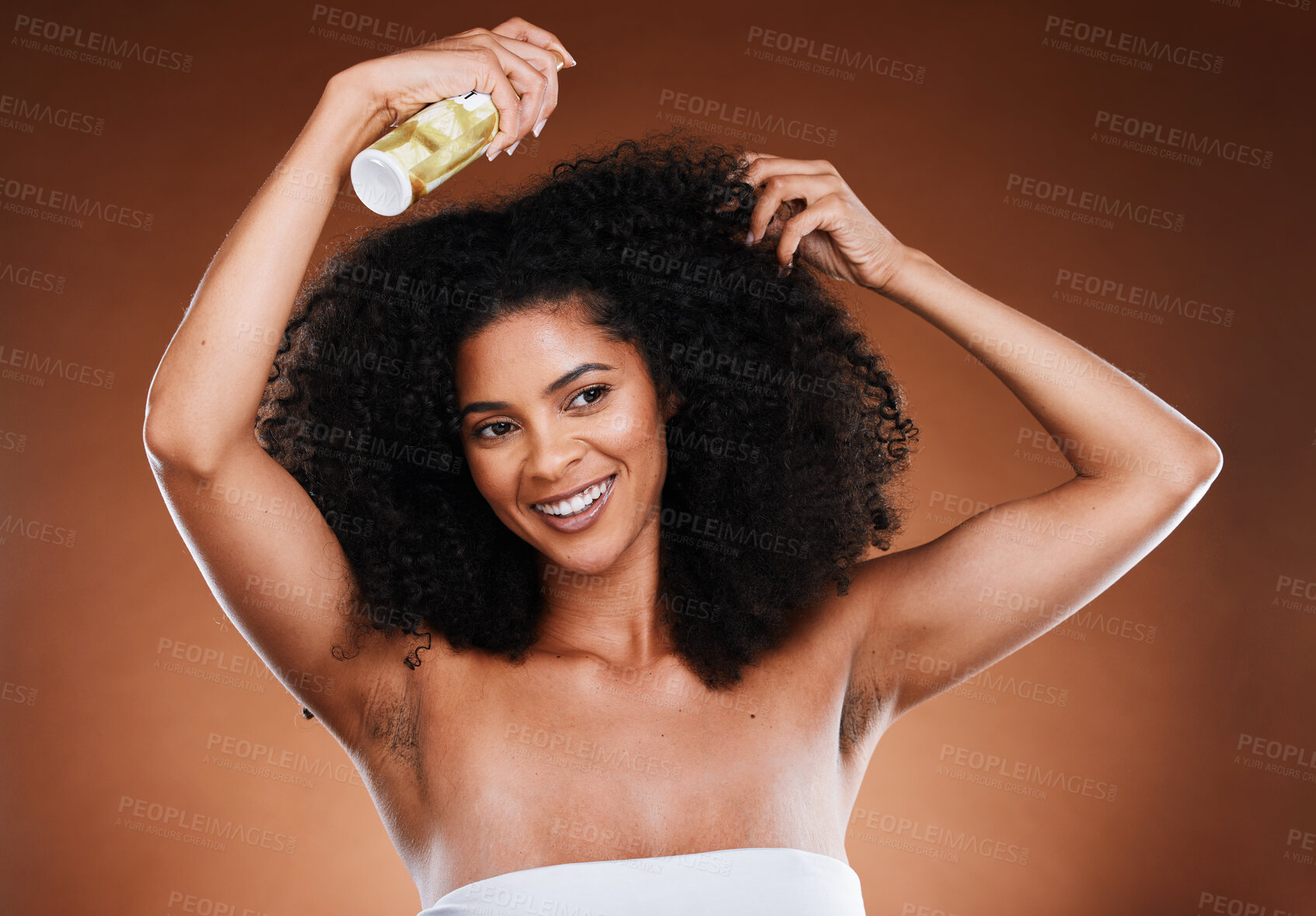 Buy stock photo Hair care, afro and spray with wellness, cosmetic and happy smile against a brown studio background with mockup. Happiness, health and care for curls with beauty, natural or  luxury cosmetics product
