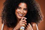 Beauty, hair care and portrait of a black woman with hair spray for natural hair routine in studio. Cosmetics, health and young African model with afro doing treatment with spray by brown background.