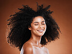 Black woman, hair care and natural afro, smile and beauty against brown studio background. Happy young african american female model face, smile and sensual with facial makeup and glowing skin