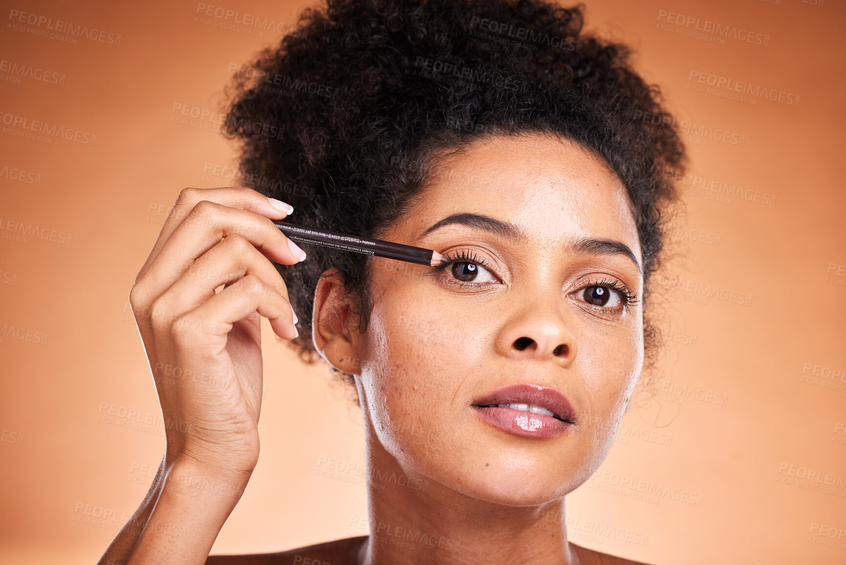 Buy stock photo Eye pencil, black woman and makeup for eyeliner, confidence or natural beauty against brown studio background. African American female, girl or cosmetics for wellness, creative and eyelash for beauty
