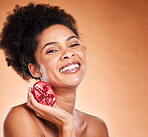 Black woman, pomegranate fruit and skincare spa wellness for beauty or hair healthcare. Cosmetics, vitamin or happy african model smile for nutrition lifestyle portrait in brown studio background