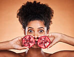 Black woman beauty, fruit and face in skincare portrait with pomegranate in by orange background. African model, woman and cosmetics studio for health, natural makeup and nutrition for skin wellness