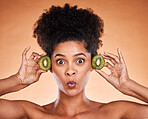 Face, beauty and kiwi with a model black woman in studio on a beige background to promote natural treatment. Portrait, cosmetics and nutrition with an attractive young female holding fruit for health