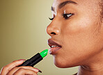 Woman, mouth and lipstick for makeup and cosmetic beauty aesthetic on a green studio background. Black woman, green lipstick glamour for lipbalm, skincare and pout treatment for plump lips
