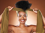 Face, beauty and black woman with hair scarf in studio on brown background. Fashion, hair care and happy female model tying her afro hair with fabric head wrap for unique hair style and healthy hair.