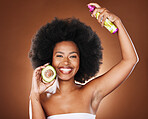 Black woman, hair care and spray with avocado, glow and afro care, smile and cosmetic product in brown studio background. Fruit, natural cosmetics and happy model smile for beauty for head nutrition