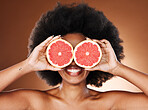 Beauty, skincare and black woman with grapefruit in hands for natural cosmetics and vitamin c facial treatment with studio background. Happy, smile and fruit covering eyes, wellness and healthy skin.