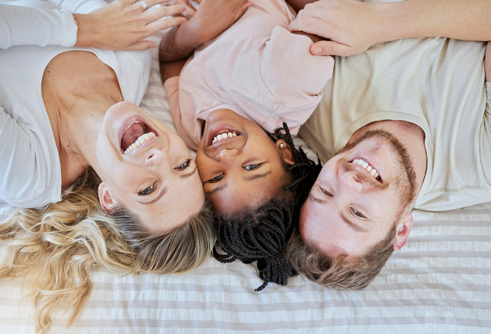 Buy stock photo Family, children and adoption with a mother, father and daughter lying on a bed in their home together. Portrait, love and kids with a man, woman and girl bonding in a house bedroom from above