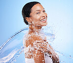 Woman, skincare and water splash, happy and cleaning body, hygiene and shower against blue studio background. Cleaning, health and luxury with happy model for cosmetics, hydration and dermatology 