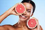 Black woman, fruit and smile for healthy skincare, cosmetics or nutrition against a blue studio background. Portrait of happy African American female holding grapefruit for vitamin C facial treatment
