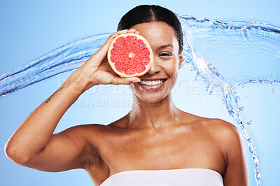 Buy stock photo Black woman, grapefruit or smile with water splash for health skincare, wellness or nutrition against a blue studio background. Portrait of happy African American girl with fruit for facial treatment