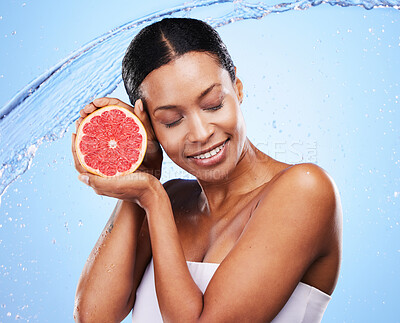Buy stock photo Grapefruit, black woman and water splash, beauty and skincare, vitamin c and healthy natural cosmetics of body wellness on studio blue background. Happy african model, wet citrus fruits and nutrition