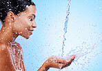 Water, splash and black woman doing skincare for health, wellness and hygiene in a studio. Beauty, shower and girl model doing a natural treatment for skin, body or face with aqua by blue background.