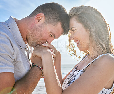 Buy stock photo Couple, beach and kiss hands with love together with happiness, smile and bonding on vacation. Man, kissing hand and woman in sunshine, holiday and happy by ocean for adventure while holding hands