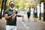 Music, time and running with a mature black man looking at his watch while out for a fitness run in the park. Workout, wellness and training with a senior male athlete or runner tracking his health