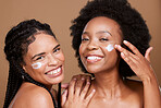 Beauty, friends and black women with face cream for skincare or moisturizing in studio on brown background. Smile, group portrait and models apply facial product or cosmetics creme for healthy skin.
