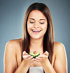 Woman, beauty and fruit with smile for skincare, nutrition or cosmetics against a studio background. Happy female holding avocado and smiling in satisfaction for natural, organic or healthy treatment