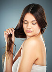 Split ends, hair care and woman with healthy, clean and soft skincare against a blue background in studio. Wellness, salon and model thinking of idea for care of hair as hairdresser on a backdrop