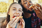 Pizza, love and happy couple eating fast food while on a date together in nature in a garden. Hungry, food and portrait of a interracial man and woman enjoying an outdoor lunch meal in a field.