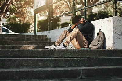 Buy stock photo Sad, depression and black man with anxiety at college, stress and headache from education on the stairs at campus. Depressed, frustrated and student with a mental health problem crying at university