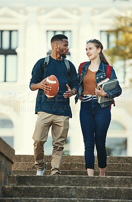 Buy stock photo Black man, woman or university students walking and talking on college, school or education learning campus. Smile, happy or interracial couple or bonding friends on steps and football or study books