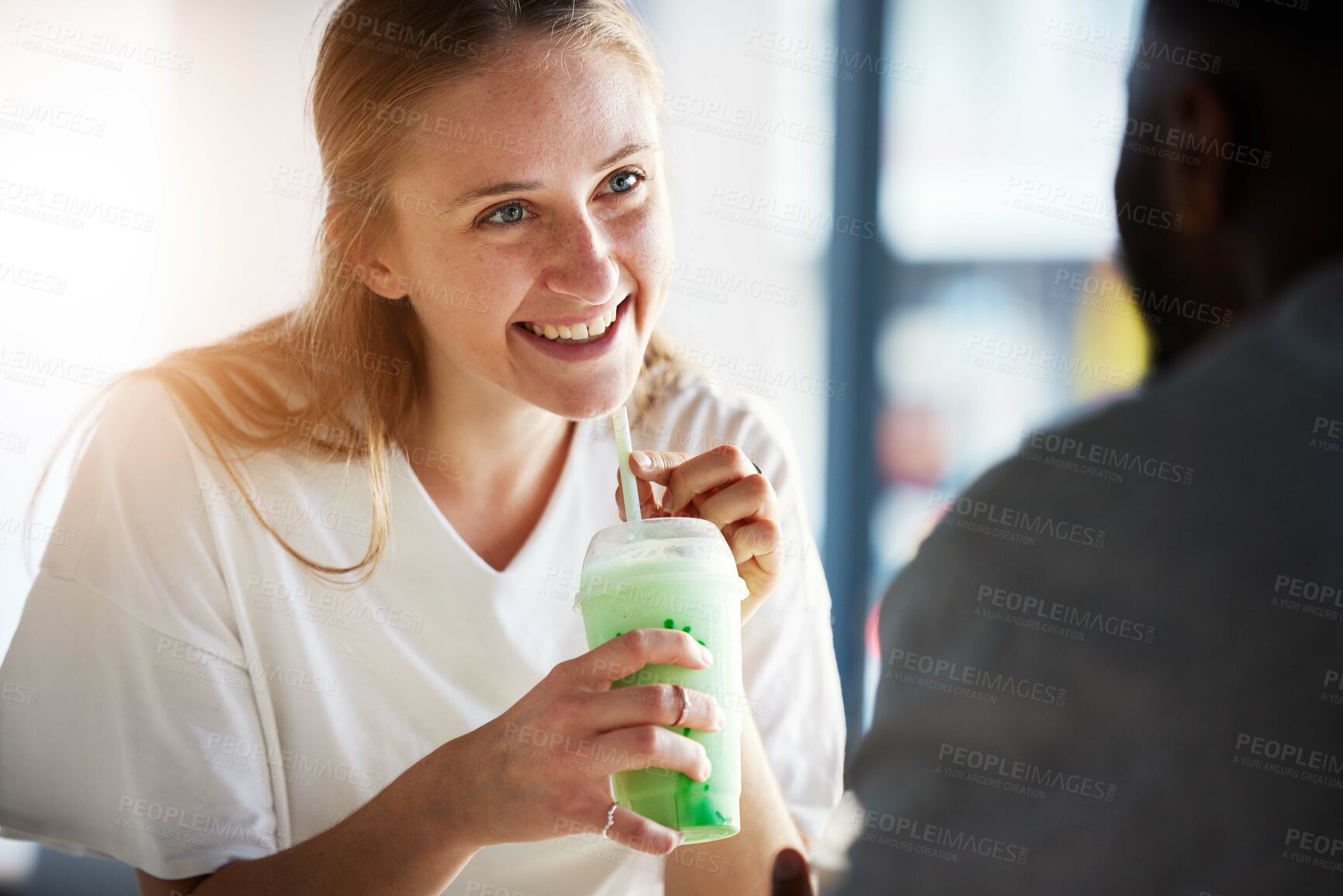 Buy stock photo Woman, smile and smoothie on date in restaurant with man in interracial relationship, love and care. Girl, happy and drinking milkshake for health, nutrition or detox in conversation with black man