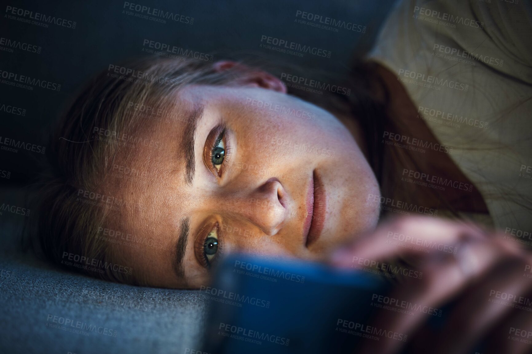 Buy stock photo Night, phone and young woman on sofa to check social media, browsing internet and online content. Technology, mobile app and girl with smartphone for texting, chatting and conversation lying on couch